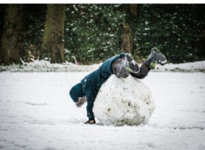Child falling over a waist-high snowball
